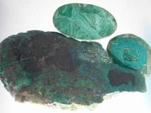 Chrysocolla with cuprite is shown in the front surrounded by Turquoise-like Chrysocolla cabs.
