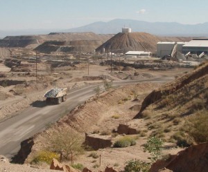 Giant dump trucks look small in the distance.